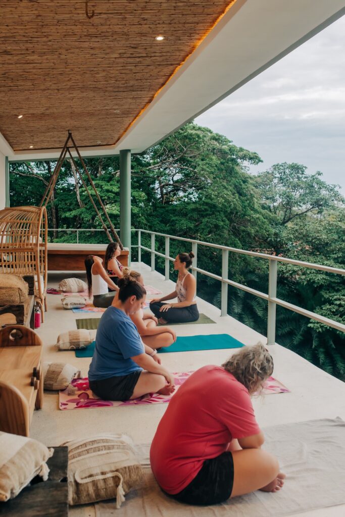 A yoga class on a deck above the trees